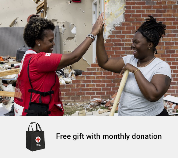 Red Cross volunteer high fives a smiling woman while they work to clean up a home destroyed by a disaster. Text below reads Free Gift with Monthly Donation next to a picture of a tote bag.