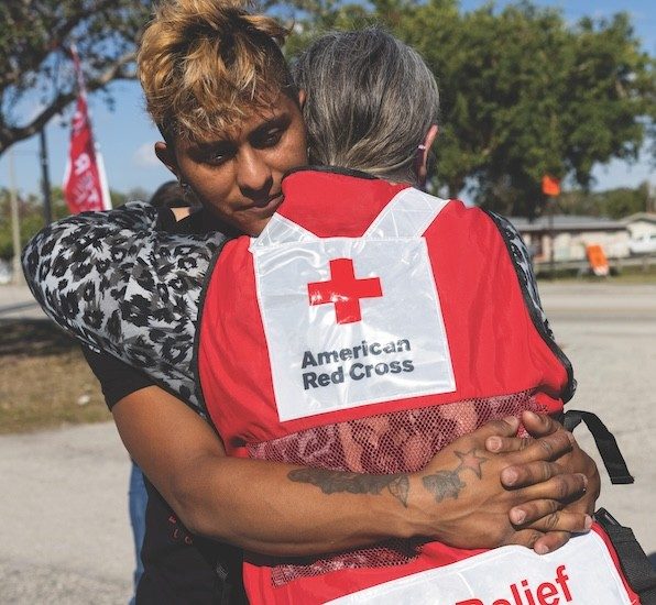A Red Cross volunteer hugs a client.